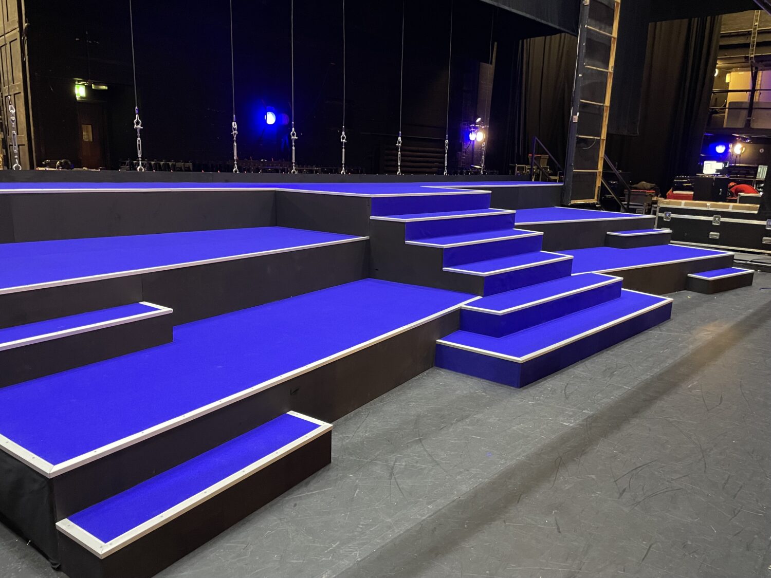 stage with tiered platforms and steps with a bright blue covering