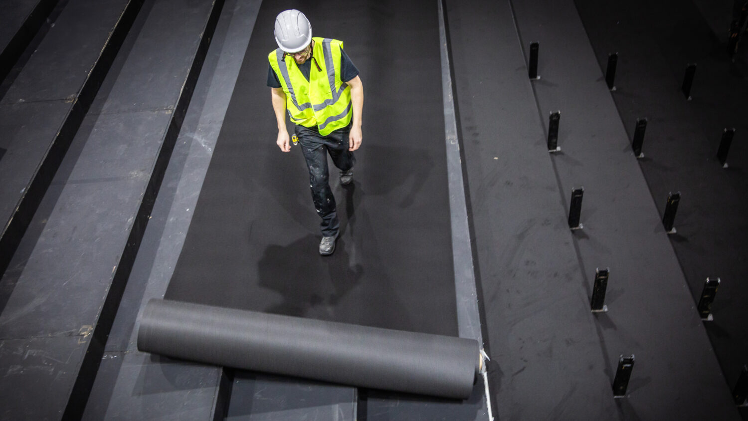 man rolling out vinyl over tiered seating